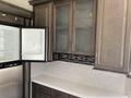 A 2021 Grand Design Recreational ST3478MBS featuring a kitchen area with glass-front cabinets and a refrigerator with an open freezer compartment
