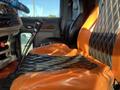 The interior of a 2009 Peterbilt Highway with black and orange quilted leather seats and a gear shift in the foreground