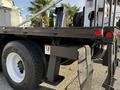 A 2011 International 7500 truck with a flatbed and visible hydraulic components including a lift arm and wheel branding showing Goodyear