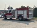 A red 1999 Freightliner FL80 fire truck with a silver compartment and various firefighting equipment on the side