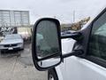 A side mirror of a 2000 Ford F-450 reflecting rain droplets on its surface