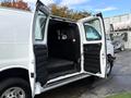 A 2023 GMC Savana with open double rear doors revealing a spacious cargo area with a protective divider and textured rubber floor