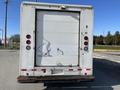 A 2012 Ford Econoline cargo van viewed from the rear with a large white door and a handle on the left side