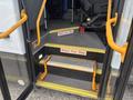A 2020 Chevrolet Express with an open door showing a set of steps and handrails designed for boarding passengers
