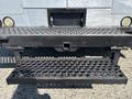 A black metal step with a perforated surface attached to a Workhorse W62 truck designed for easy access to the vehicle's rear area