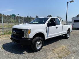 A 2017 Ford F-250 SD in white with a standard cab and bed, featuring chrome accents and all-terrain tires parked at an open space