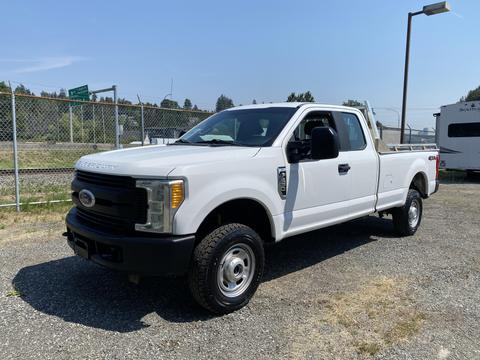 A 2017 Ford F-250 SD in white with a standard cab and bed, featuring chrome accents and all-terrain tires parked at an open space