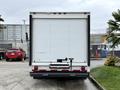 A white 2022 Ford E-450 box truck viewed from the rear with a large cargo door and a hitch attachment beneath the bumper