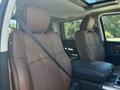 The interior of a 2015 RAM 1500 showing two plush brown leather front seats with seatbelts and a black center console between them