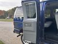 A blue 2013 Ford E-350 Super Duty van with the side door open revealing the interior seating area