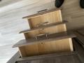 Three stacked wooden drawers with handles are displayed open, revealing their empty interiors. The drawers have a smooth finish and a simple design.