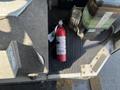 A red fire extinguisher is placed on the floor of a vehicle next to a black and green object
