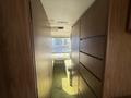 A 1976 GMC Motorhome interior hallway with wood paneling and green carpet leading to a sleeping area with a bed and a window at the end