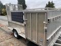 A metallic trailer equipped with solar panels on one side and a lockable storage compartment on the other side