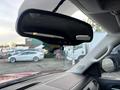 A rearview mirror hanging from a windshield with a small ornament attached depicting a colorful silhouette of a state