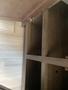 A wooden cabinet or storage unit with open shelves and a metal latch in a recreational vehicle interior