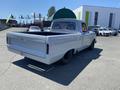 A 1962 Ford 2WHDR pickup truck with a silver body and red interior parked with its cargo bed visible and a green canopy mounted in the bed
