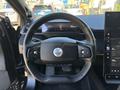 A close-up view of the steering wheel and dashboard of a 2023 Fisker Ocean featuring a minimalist design and digital display