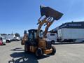 A 2016 Case 580 Super N backhoe loader with a raised bucket in front and a front loader attachment ready for operation