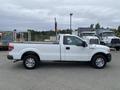 A white 2013 Ford F-150 pickup truck with a flatbed and chrome wheels is positioned in profile view