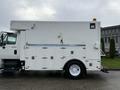 A 2011 International 4400 truck modified with a large white utility body featuring multiple compartments and a yellow light on the roof