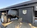 A 2014 Ford F-550 with a flatbed design featuring a storage compartment and a chained spare tire mounted underneath