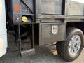A close-up view of a 2021 Ford F-350 SD with a flatbed and a toolbox mounted on the side featuring a lock and textured surface
