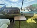 Interior view of a 1976 GMC Motorhome featuring a wooden dashboard a vintage stereo system and a small folding table next to a green upholstered seat