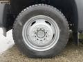 A close-up of a silver wheel of a 2015 Ford F-450 featuring a large tire with deep treads and multiple lug nut holes
