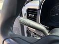 Close-up of the control stalk for headlights and windshield wipers on a 2021 Ford F-150 with a circular speedometer visible in the background