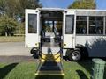 A 2019 Chevrolet Express bus with an open entrance featuring a yellow wheelchair ramp and two blue seats visible inside