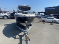 A 2013 Larson 238 boat with a sleek design is displayed on a trailer facing forward in an outdoor setting