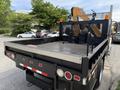 A 2011 International 4300 flatbed truck with a steel bed and tools visible in the cargo area