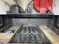 A 2016 RAM 1500 truck bed with black rubber flooring, wooden planks, and equipment including a red air compressor and battery in the corner