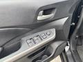 The interior door panel of a 2014 Honda CR-V featuring control buttons for windows and door locks in a black finish