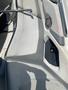 A white leather boat seat with a speaker and cupholder integrated into the design, showing some wear and sun exposure