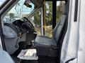 Interior view of a 2018 Ford Transit-350 showing the driver's seat dashboard and controls with a gray seat and floor mat in the foreground