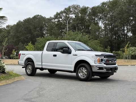 A 2018 Ford F-150 parked with a white exterior and chrome accents featuring a four-door cab and all-terrain tires