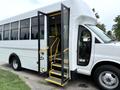 A 2015 Chevrolet Express bus with an open door revealing yellow steps leading inside