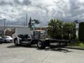 A 2022 Lion Lion6 electric truck in a parking area with a white cab and a flatbed chassis, showcasing its modern design and utility features
