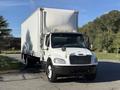 A 2012 Freightliner M2 106 box truck with a white cargo area and black front bumper parked on a street
