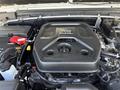 Close-up of a Jeep Wrangler engine showcasing a black engine cover with the Jeep logo and various engine components like hoses and a battery terminal