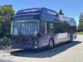 A blue and white 2018 Grande West Vicinity bus with large windows and the word TRAN SIT displayed on the front, designed for public transit services