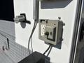 A 2011 Ford F-550 featuring an electrical outlet mounted on the vehicle's side with a gray protective cover and a visible power plug connected