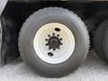 A close-up of a large black tire mounted on a white wheel featuring multiple bolt holes and a metal hub assembly