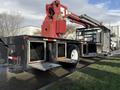 A 2010 International 4300 truck with a mounted crane extending from the rear, featuring a flatbed and side storage compartments