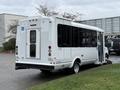 A white 2013 Chevrolet Express shuttle bus with a side door and wheelchair access features, showcasing a spacious design suited for transporting passengers