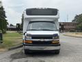 A front view of a 2020 Chevrolet Express with a white body and black roof featuring side mirrors and a grille with the Chevrolet logo
