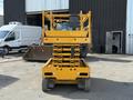 A yellow 2013 Haulotte Compact scissor lift with a raised platform and four wheels positioned in a workshop setting