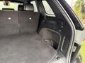Interior trunk space of a 2019 Jeep Grand Cherokee with a folded rear seat and black carpeting